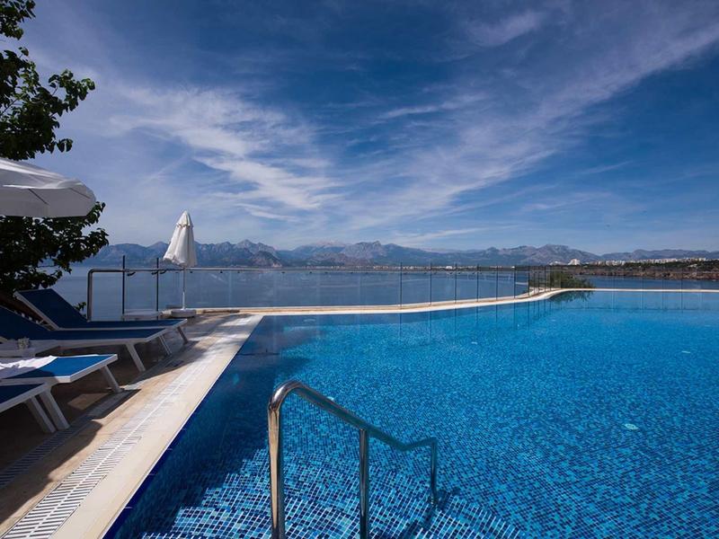 Aantrekkelijk zwembad met helderblauw water en ligstoelen met uitzicht op een meer en bergen.