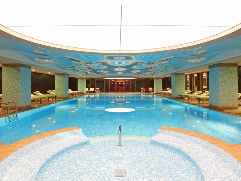 Overdekt zwembad met warme verlichting, ruime omgeving en comfortabele ligstoelen.