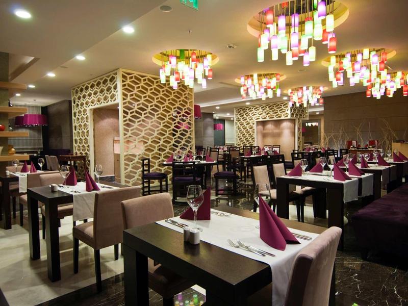 Elegant hotelrestaurant met gedekte tafels en moderne kroonluchters.