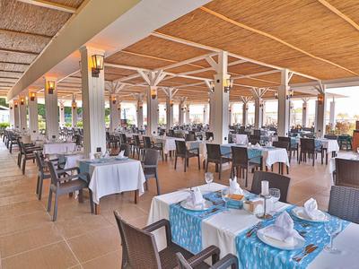 Grande ristorante aperto con tavoli apparecchiati e tetto in vimini.