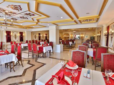 Sala da pranzo elegante con sedie rosse e bianche e tavoli apparecchiati con luce calda.