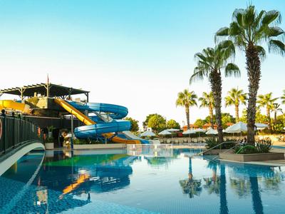 Piscina con scivoli d'acqua e palme in una località di vacanza soleggiata
