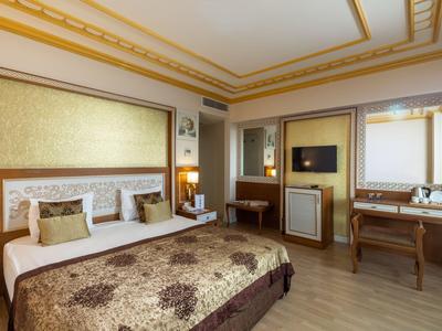 Elegante camera d'albergo con letto grande, accenti dorati e scrivania in ferro battuto.