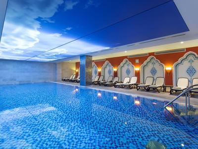 Piscina interna lussuosa con superficie piastrellata blu e comode sedie a sdraio.