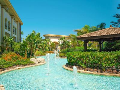 Hotel con piscina esterna, giardino e area coperta per sedersi con tempo soleggiato.