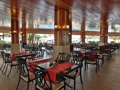 Ampia sala da pranzo di un hotel aperta con molti tavoli e sedie sotto un soffitto di legno.