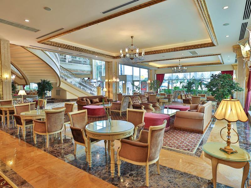 Area lounge elegante dell'hotel con poltrone, tavoli e tappeti sotto i lampadari.