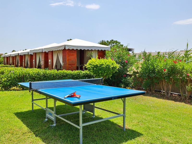 Giardino verde con tavolo da ping pong e bungalow in fila sullo sfondo con tempo soleggiato