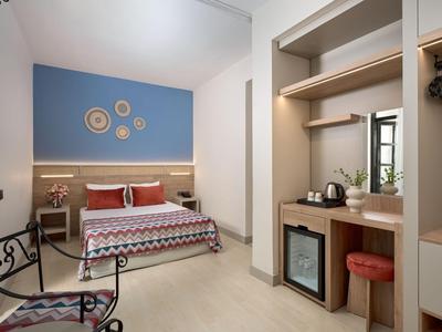 Modern eingerichtetes Hotelzimmer mit Bett, Schreibtisch, Stuhl und dekorativer Wandgestaltung.