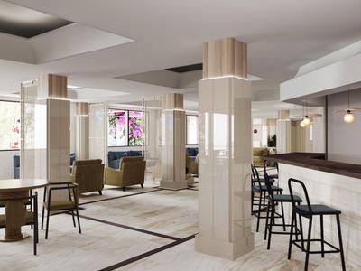 Moderner Hotel-Loungebereich mit Stühlen, Tischen und einer Bar neben beige gefliesten Säulen.