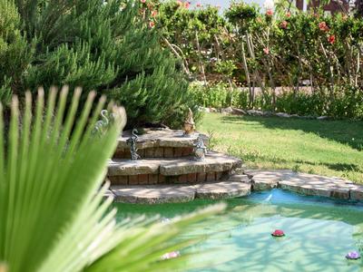 Schwimmbecken mit Wasserspielen und umgebender Gartenanlage mit Grünpflanzen
