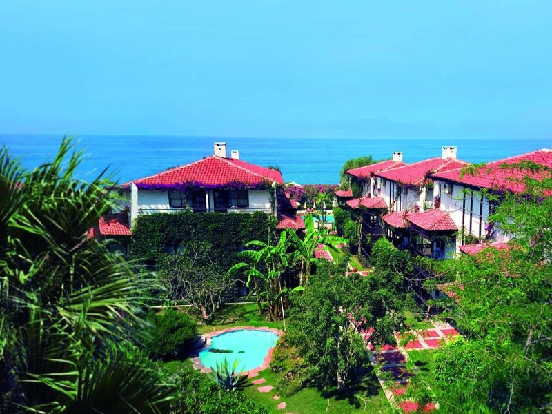Hôtel entouré de végétation luxuriante avec vue sur la mer et piscine.