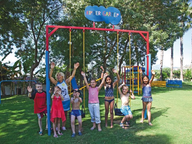Enfants joyeux jouant sur une balançoire dans un parc ensoleillé d'hôtel.