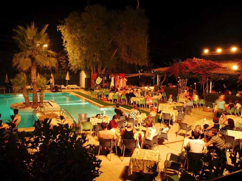 Soirée animée autour d'une piscine éclairée avec des tables et des invités.