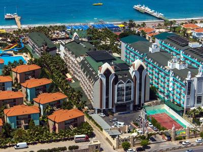 Hotelanlage mit Pools, roten Dächern und direktem Zugang zum blauen Meer am Strand.