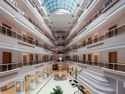 Innenansicht eines großen Hotels mit mehreren Etagen, weißen Wänden, Treppen und Glasdach.