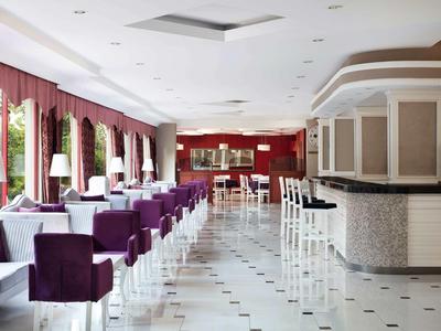 Eleganter Raum mit lila Sesseln, weißen Barhockern und roten Wänden in einem modernen Interieur.