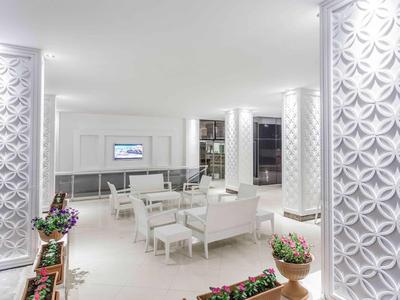 Heller, moderner Raum mit weißen Möbeln, dekorativen Wänden und Pflanzen in Blumentöpfen.