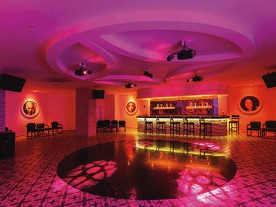 Modern bar with illuminated counter and dance floor in warm pink lighting