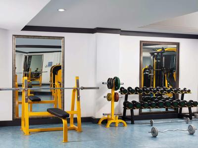 Modern gym room with weight benches and mirrors in a hotel.