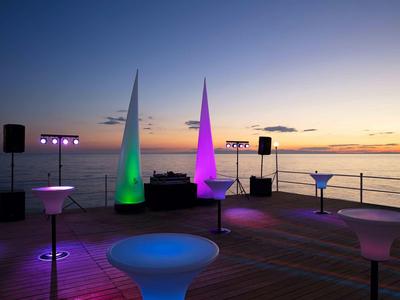 Evening beach bar with colorful lights and sea view at sunset.
