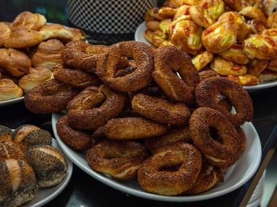 Verschiedene Arten von frisch gebackenem Gebäck, darunter Simits, Brötchen und Sesamringe, auf Tellern.