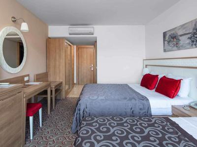 Hotel room with two beds, wooden furniture, TV, and stylish decor in neutral tones.