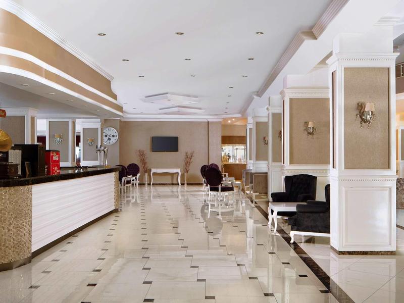 Heller Empfangsbereich mit Sitzgelegenheiten, Theke, Pendelleuchten und Marmorfliesenboden.