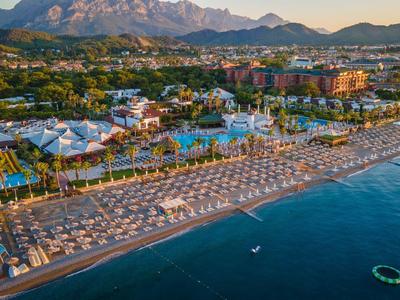 Spiaggia con lettini e resort tropicale vicino alle montagne al tramonto.