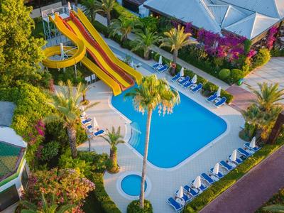 Vista di una piscina con scivoli gialli e lettini in un hotel tropicale.