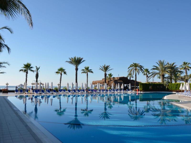 Grande piscina con palme e lettini in un resort soleggiato per le vacanze.