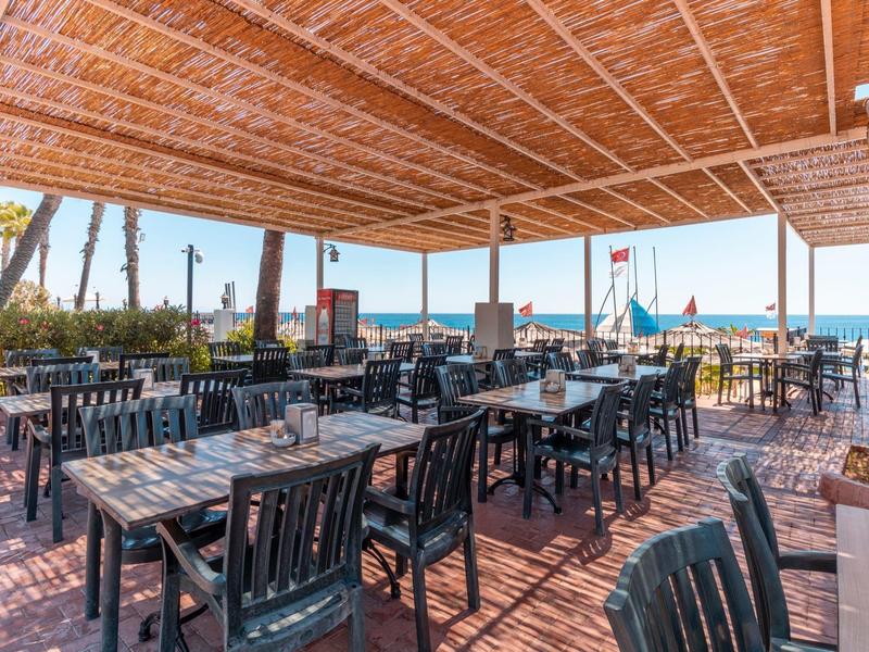 Terrazza esterna coperta con più tavoli e sedie, vista mare.