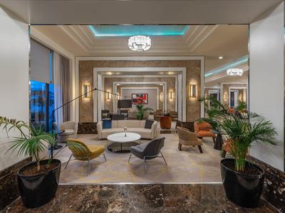 Lobby d'hôtel élégante avec espaces de sièges stylés, plantes vertes et éclairage moderne.