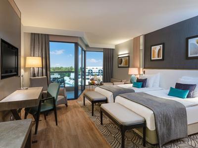 Chambre d'hôtel moderne avec lit double, balcon et vue sur l'eau.