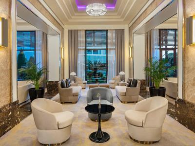 Lobby d'hôtel luxueuse avec fauteuils confortables, tables et grandes fenêtres donnant sur l'extérieur.