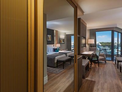 Chambre d'hôtel moderne avec lit double, sol en bois et balcon avec vue.