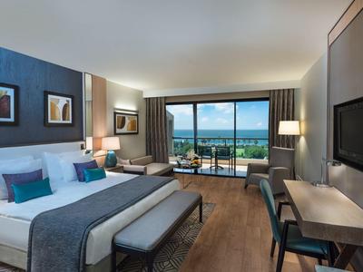 Chambre d'hôtel moderne avec lit double, coin salon et balcon avec vue sur la mer.