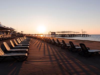 Chaises longues vides sur la plage au coucher du soleil avec vue sur une jetée.