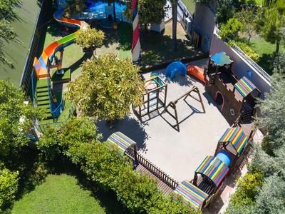 Vogelperspektive auf einen farbenfrohen Kinderspielplatz mit Rutsche, Schaukeln und Sitzbereich.