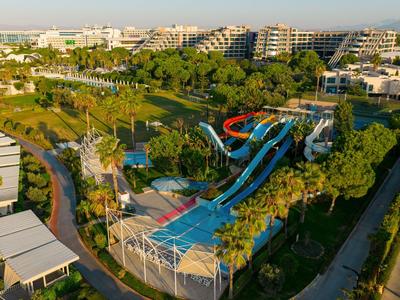 Blick auf ein Hotelresort mit Wasserrutschen und grünen Palmengärten bei Sonnenlicht.