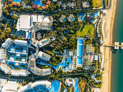 Luftaufnahme eines Hotelresorts mit Pools und direktem Zugang zu einem Sandstrand.
