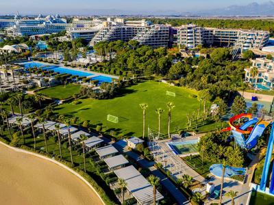 Große Hotelanlage mit Pools, Wasserrutschen, grünen Rasenflächen und Sandstrand am Meer.