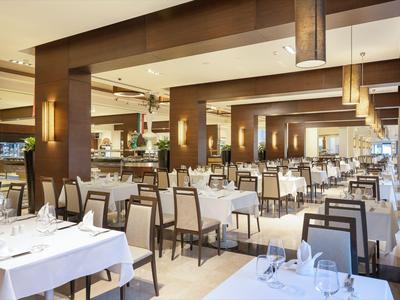 Hell eingerichteter Hotelrestaurantbereich mit weiß gedeckten Tischen und braunen Holzverkleidungen.