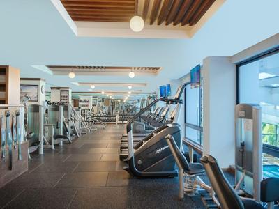 Moderner Fitnessraum mit Laufbändern und Gewichten neben großen Fenstern mit Aussicht.