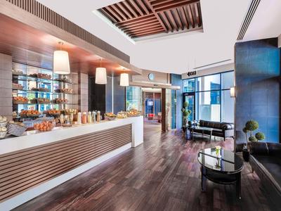 Moderna recepción de hotel con mostrador, área de descanso y suelo de madera.