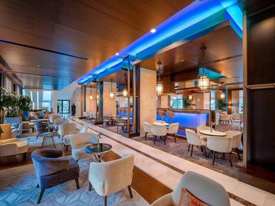 Restaurante moderno de hotel con sillas cómodas, paredes de madera e iluminación azul.