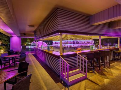 Bar del hotel con iluminación moderna y asientos en tonos morados y cálidos.