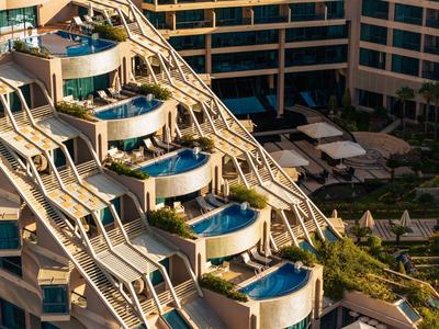Terrazas de hotel de varios niveles con piscinas privadas y tumbonas ofrecen comodidad de lujo para vacaciones.