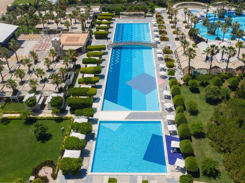Une piscine d'hôtel de luxe avec plusieurs bassins entourés de palmiers et de chaises longues.