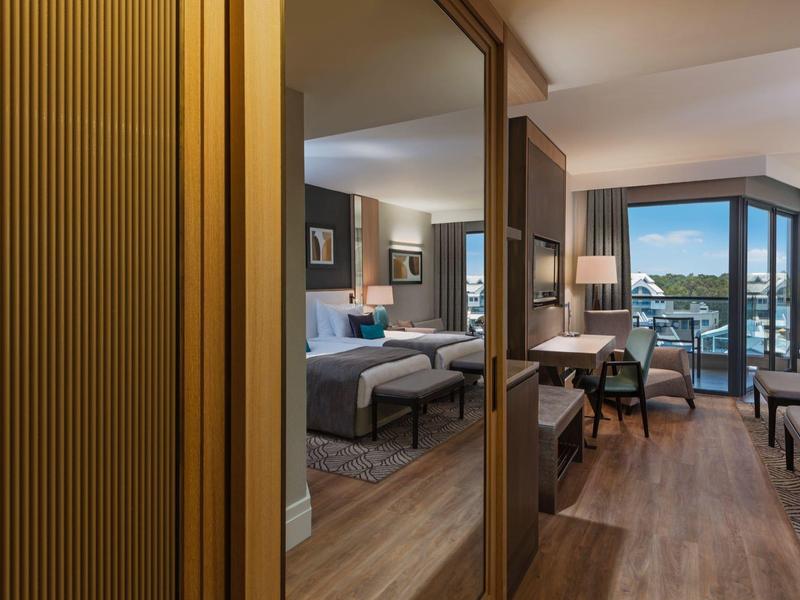 Chambre d'hôtel moderne avec lit double, sol en bois et balcon avec vue.